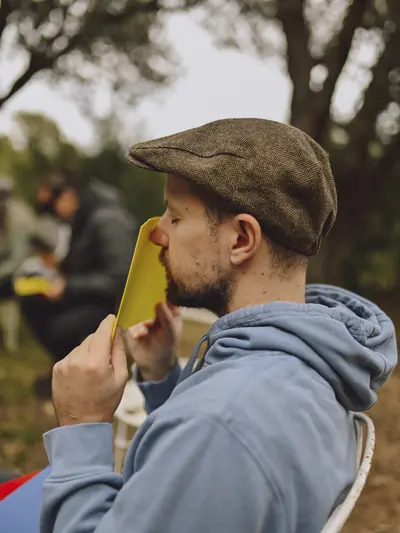 Participante con gorra explorando una cartulina amarilla con los ojos cerrados