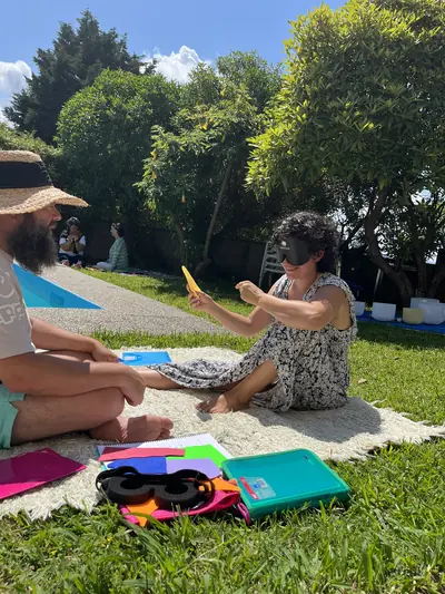 Dos personas con antifaz trabajando con una cartulina amarilla durante una práctica en el jardín