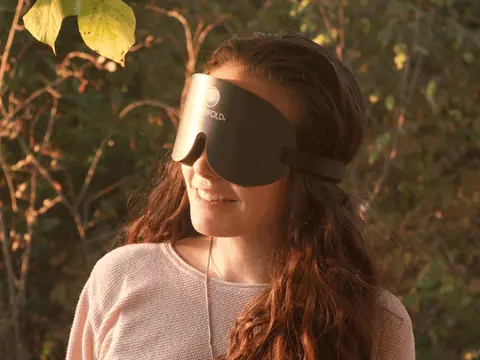 Mujer con antifaz entre las hojas, con luz de atardecer