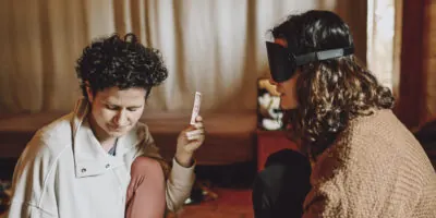 Facilitadora mostrando una tarjeta a una participante con antifaz
