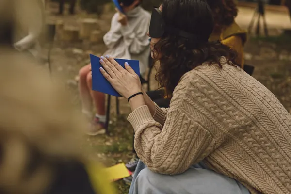 Personas sentadas entre las encinas, con antifaz, palpando cartulinas de colores