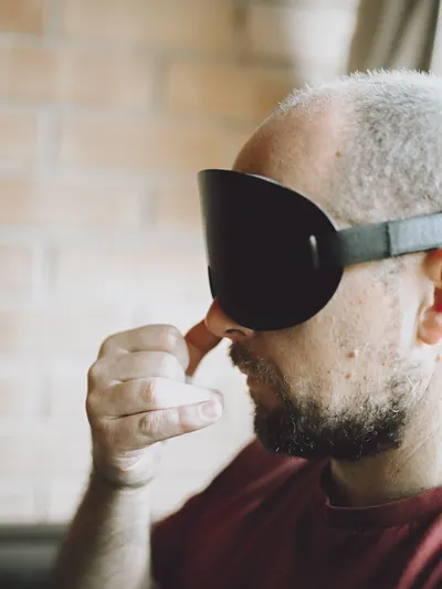 Hombre con antifaz acercando los dedos a la cara durante un ejercicio de percepción